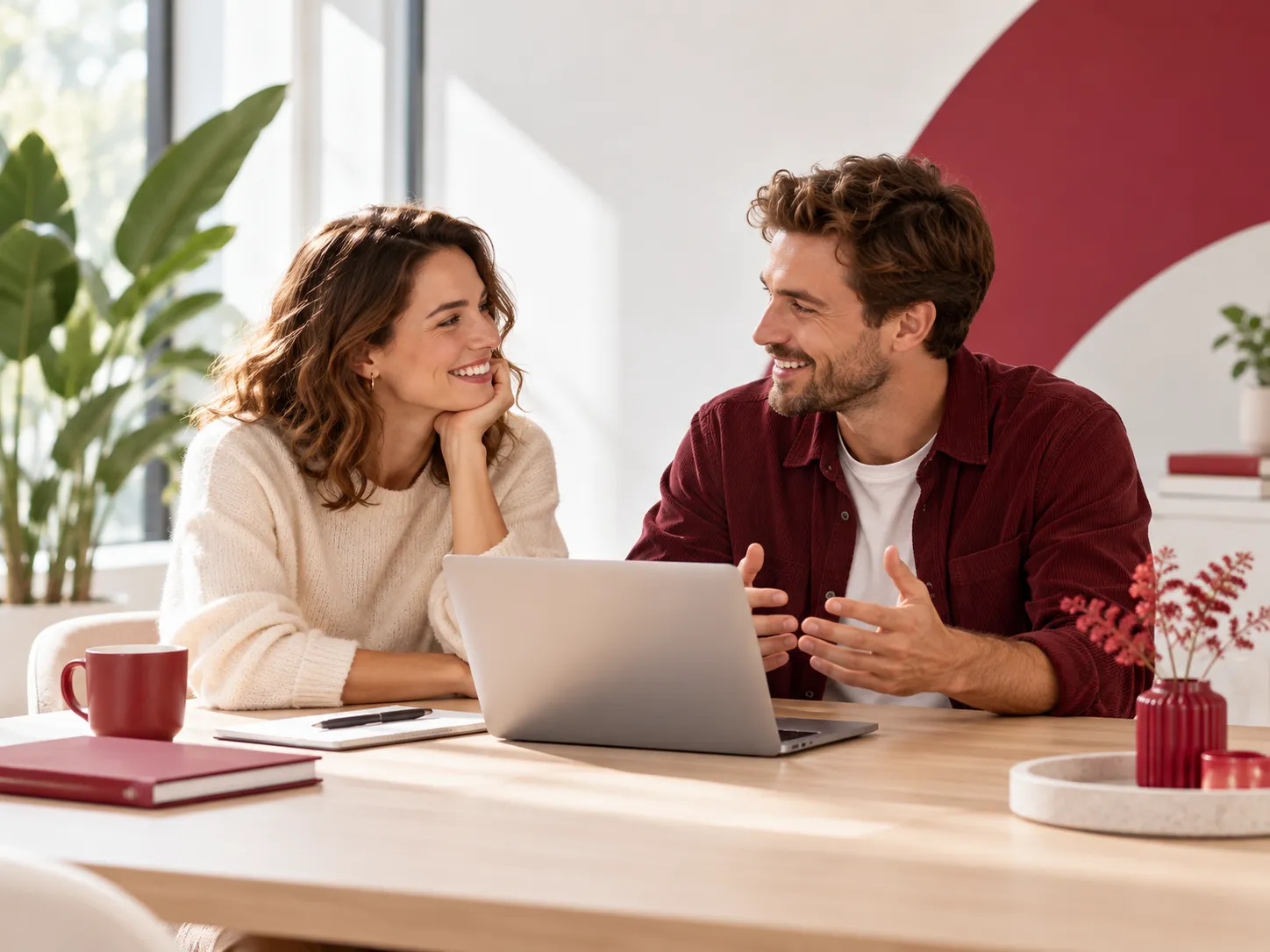 Twee mensen bespreken samen iets achter een laptop in een warme en moderne werkomgeving